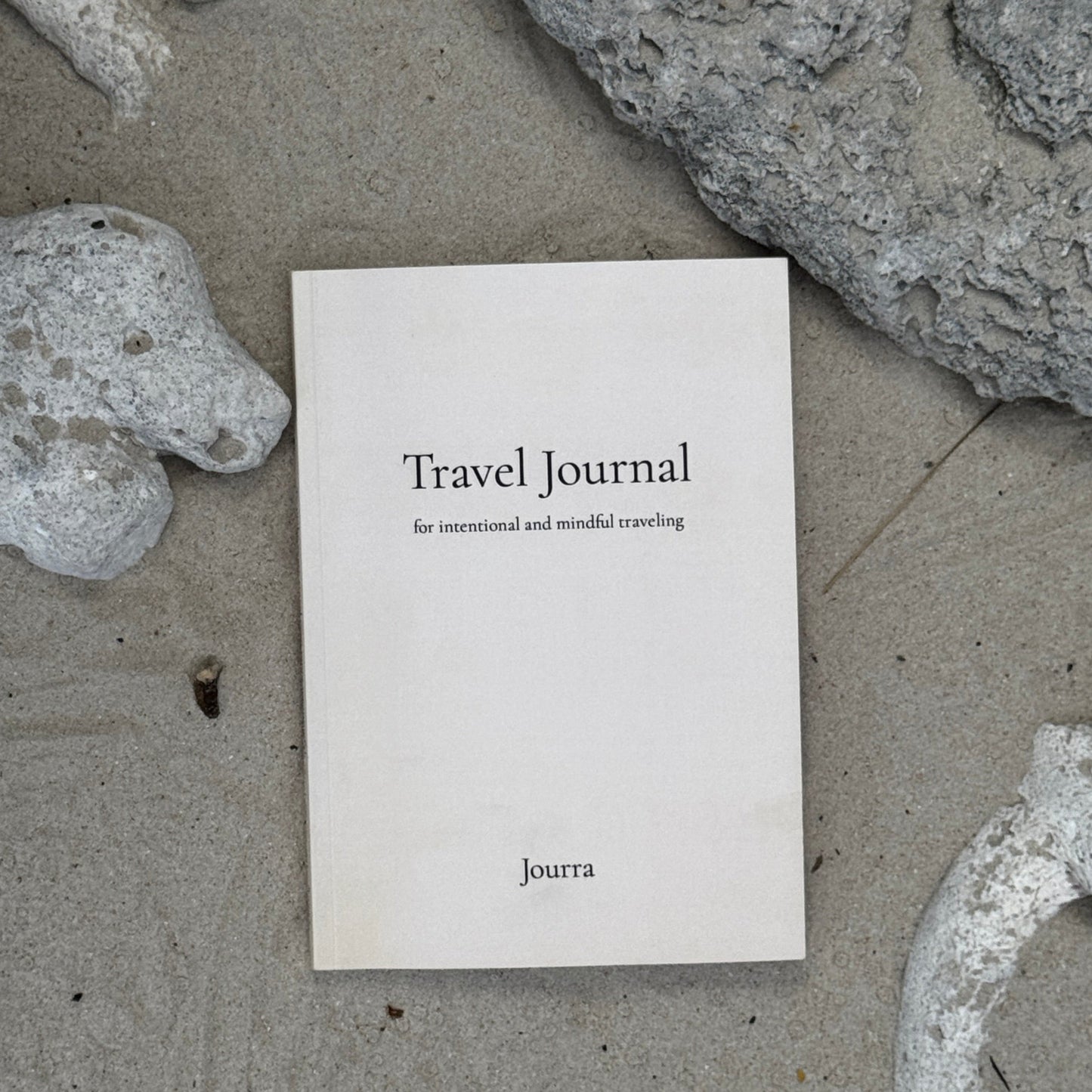 Travel journal on a sandy surface with rocks