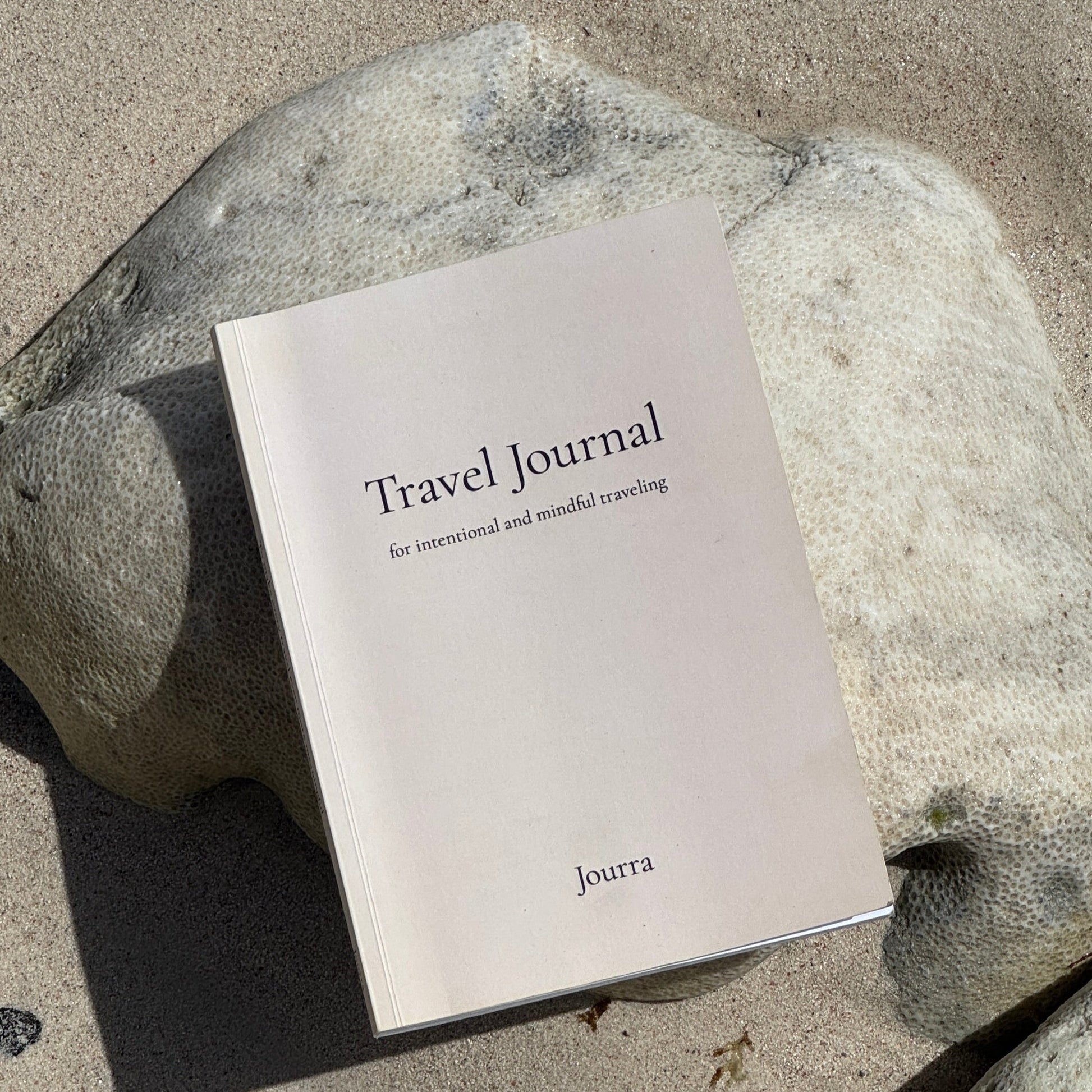 Travel journal on a rock with sand in the background